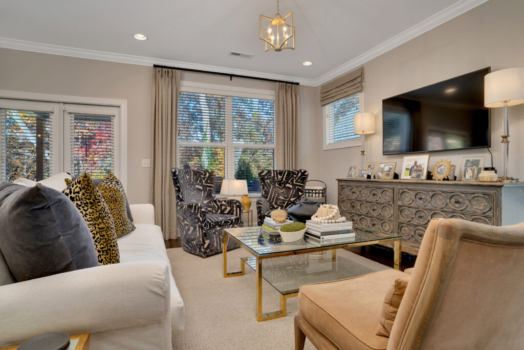 Living room with couch and chairs facing tv. Drapery over window and matching Roman shade