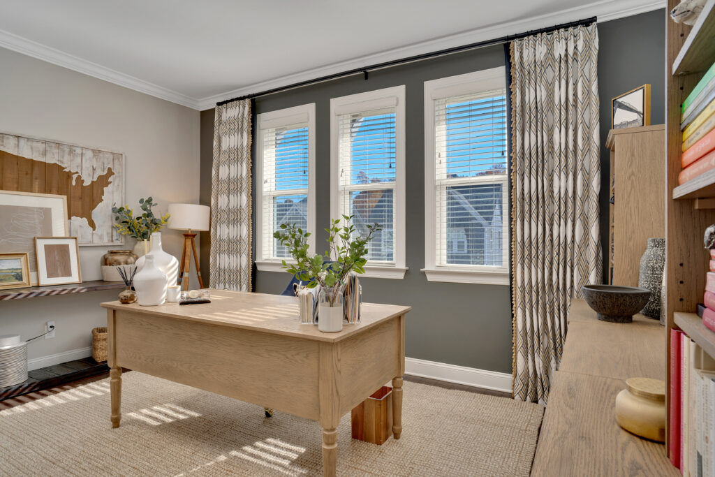 Office with bookshelves, light wood, and custom drapery with tassel trim. 