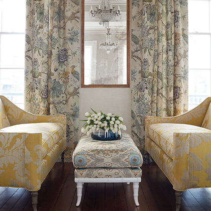 Sitting area with yellow sofas, upholstered ottoman, and drapery panels created with Thibaut Fabric