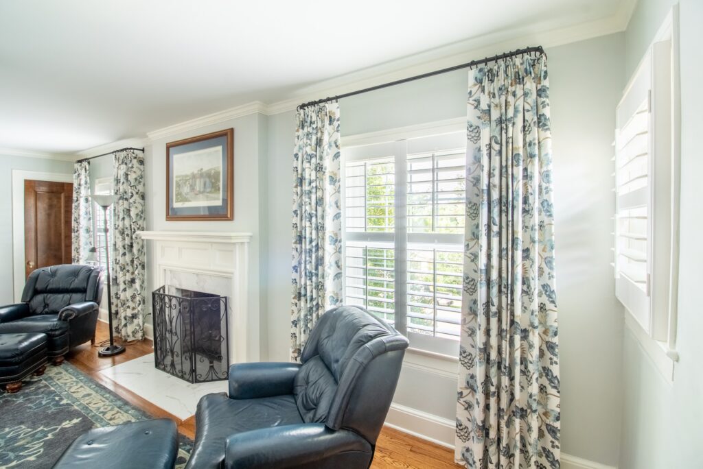 Blue and white drapery layered with plantation shutters between a fireplace. 