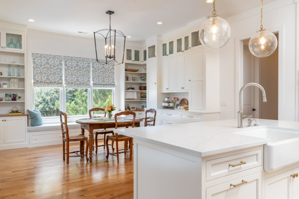 all white kitchen overlooking kitchen table and window seat with blue and gold custom roman shades in chattanooga