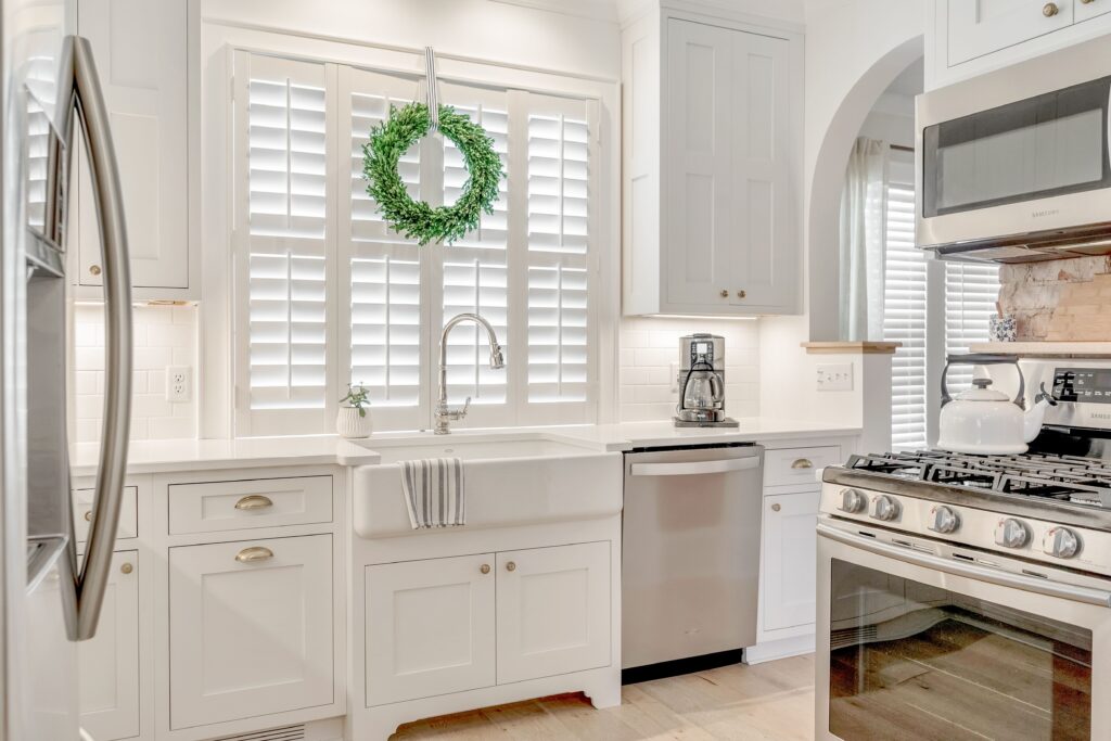all white kitchen with white interior shutters above the farmhouse sink