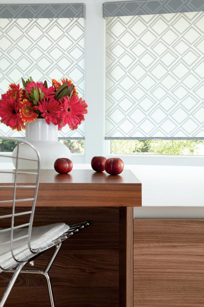 Roller shades in a kitchen with red daises in a vase on the counter