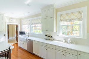 Patterned Roman shades covering windows in brightly lit kitchen