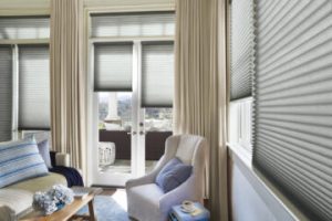 Gray honeycomb shades covering windows and patio doors in home living room